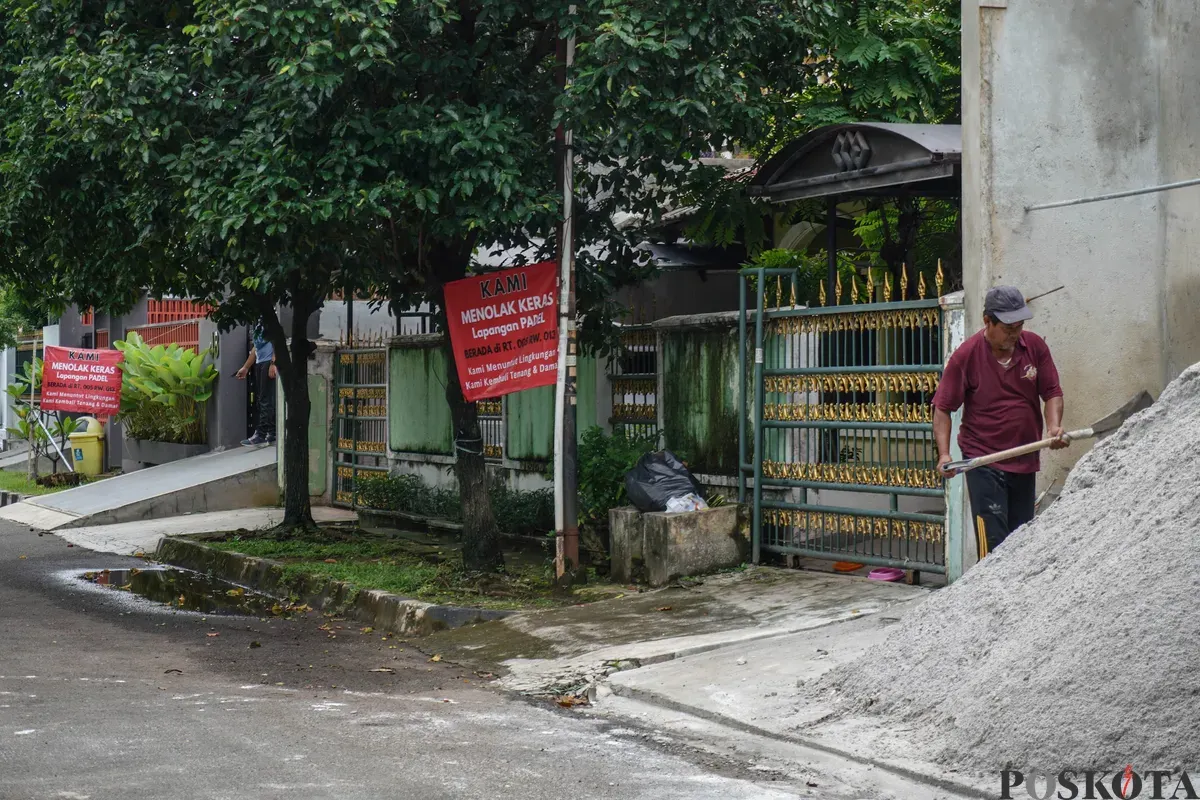 Warga berjalan melewati spanduk penolakan lapangan padel di Jalan Pulomas Barat II, Kayu Putih, Jakarta Timur, Minggu, 22 Februari 2026. (Sumber: Poskota/Bilal Nugraha Ginanjar)