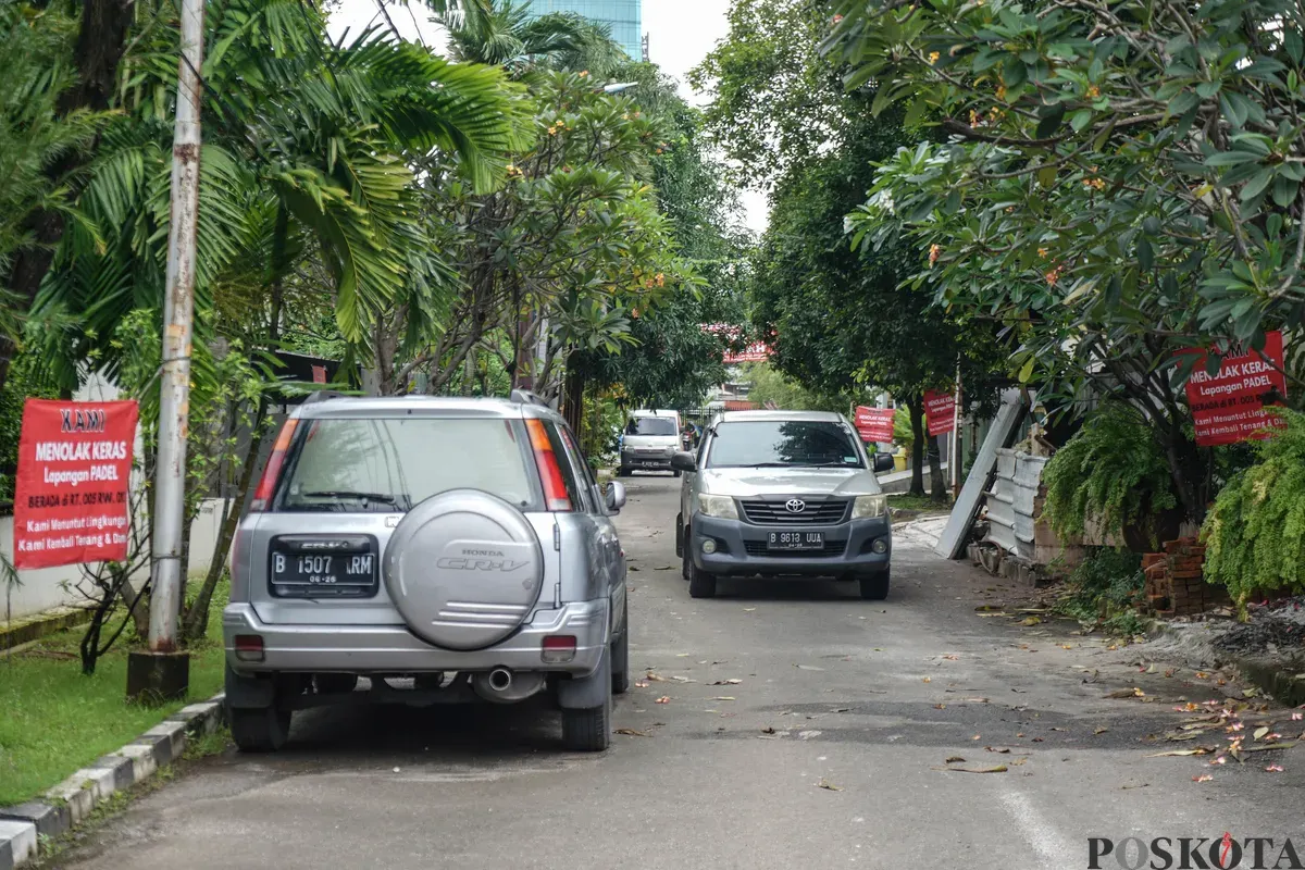 Warga berjalan melewati spanduk penolakan lapangan padel di Jalan Pulomas Barat II, Kayu Putih, Jakarta Timur, Minggu, 22 Februari 2026. (Sumber: Poskota/Bilal Nugraha Ginanjar)