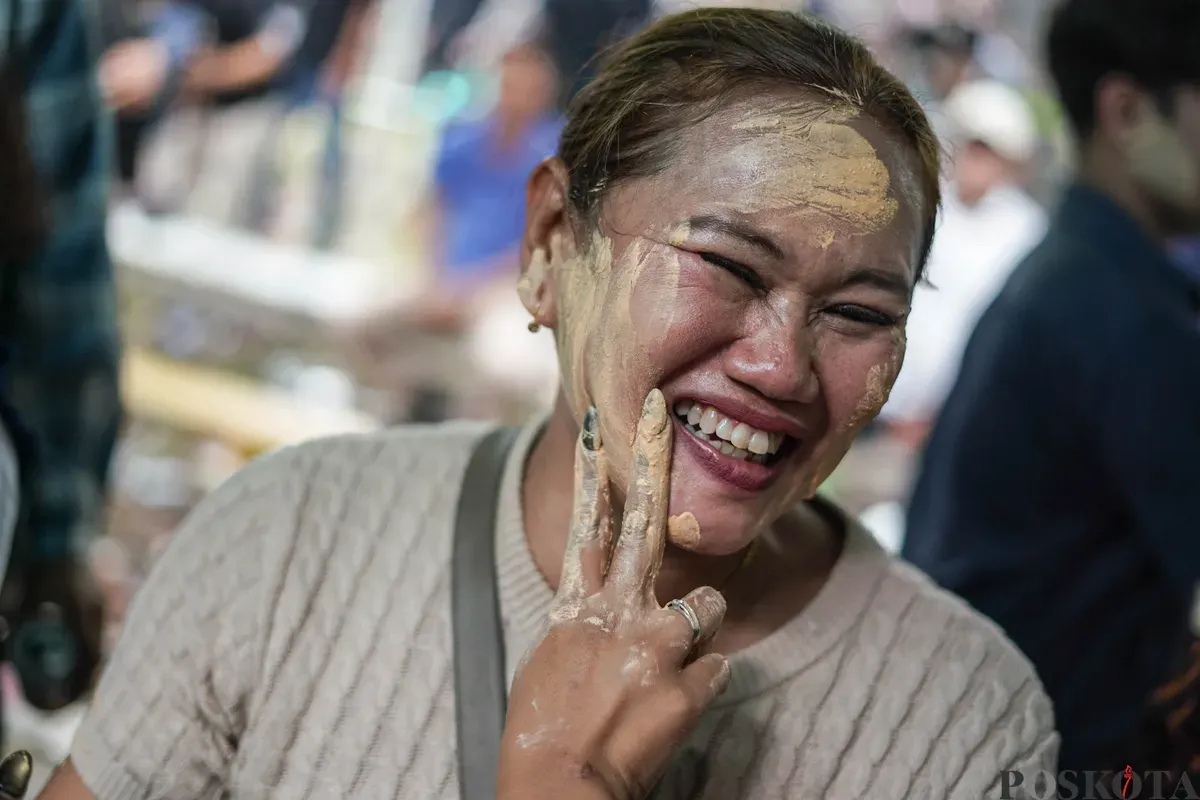 Orang Tugu menari sembari saling mencorengkan bedak saat mengikuti acara adat dan budaya Mandi-mandi di Kampung Tugu, Cilincing, Jakarta, Minggu, 4 Januari 2026. (Sumber: Poskota/Bilal Nugraha Ginanjar)