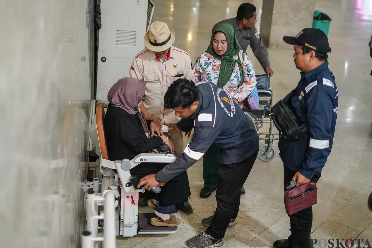 Warga membantu penyandang disabilitas menaiki lift chair atau kursi angkat di kawasan Monumen Nasional (Monas), Jakarta, Rabu, 7 Januari 2026. (Sumber: Poskota/Bilal Nugraha Ginanjar)