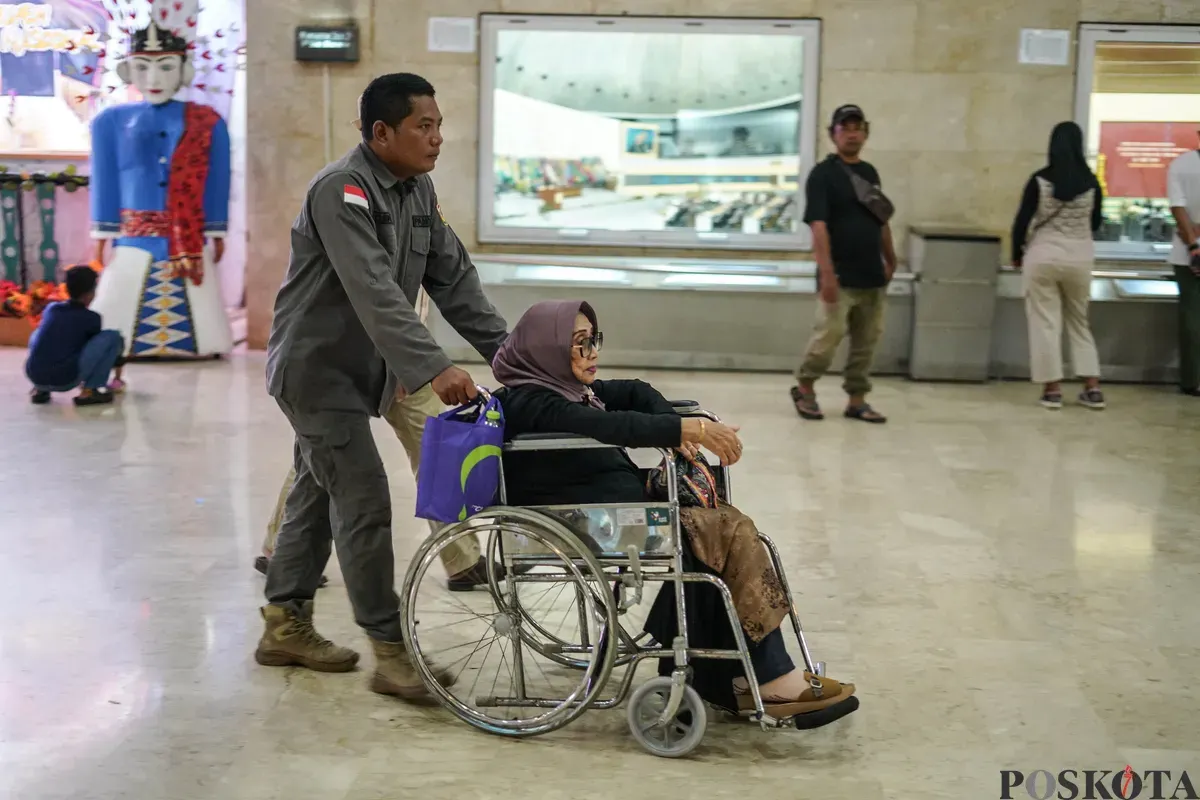 Warga membantu penyandang disabilitas menaiki lift chair atau kursi angkat di kawasan Monumen Nasional (Monas), Jakarta, Rabu, 7 Januari 2026. (Sumber: Poskota/Bilal Nugraha Ginanjar)