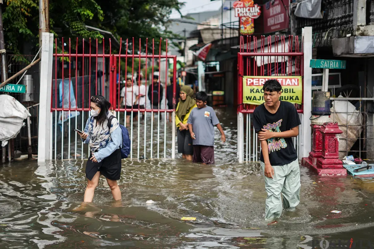 Warga berjalan melintasi banjir di Jalan Latumenten, Jelambar, Jakarta Barat, Jumat, 23 Januari 2026. (Sumber: Poskota/Bilal Nugraha Ginanjar)
