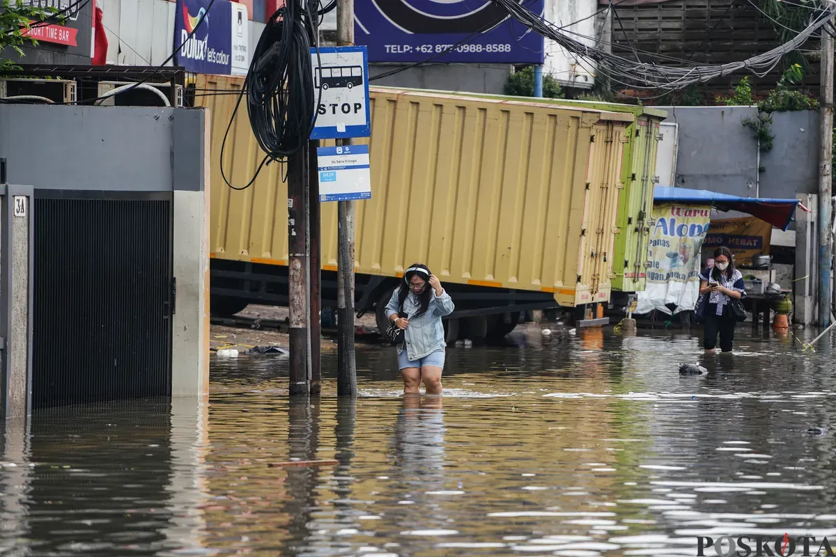 Warga berjalan melintasi banjir di Jalan Latumenten, Jelambar, Jakarta Barat, Jumat, 23 Januari 2026. (Sumber: Poskota/Bilal Nugraha Ginanjar)