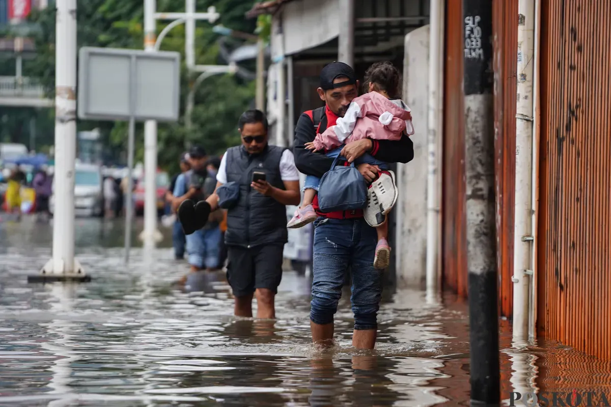 Warga berjalan melintasi banjir di Jalan Latumenten, Jelambar, Jakarta Barat, Jumat, 23 Januari 2026. (Sumber: Poskota/Bilal Nugraha Ginanjar)