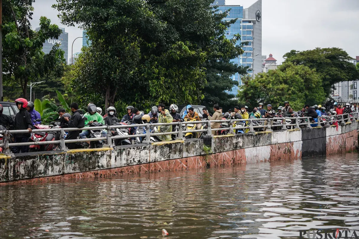 Warga berjalan melintasi banjir di Jalan Latumenten, Jelambar, Jakarta Barat, Jumat, 23 Januari 2026. (Sumber: Poskota/Bilal Nugraha Ginanjar)