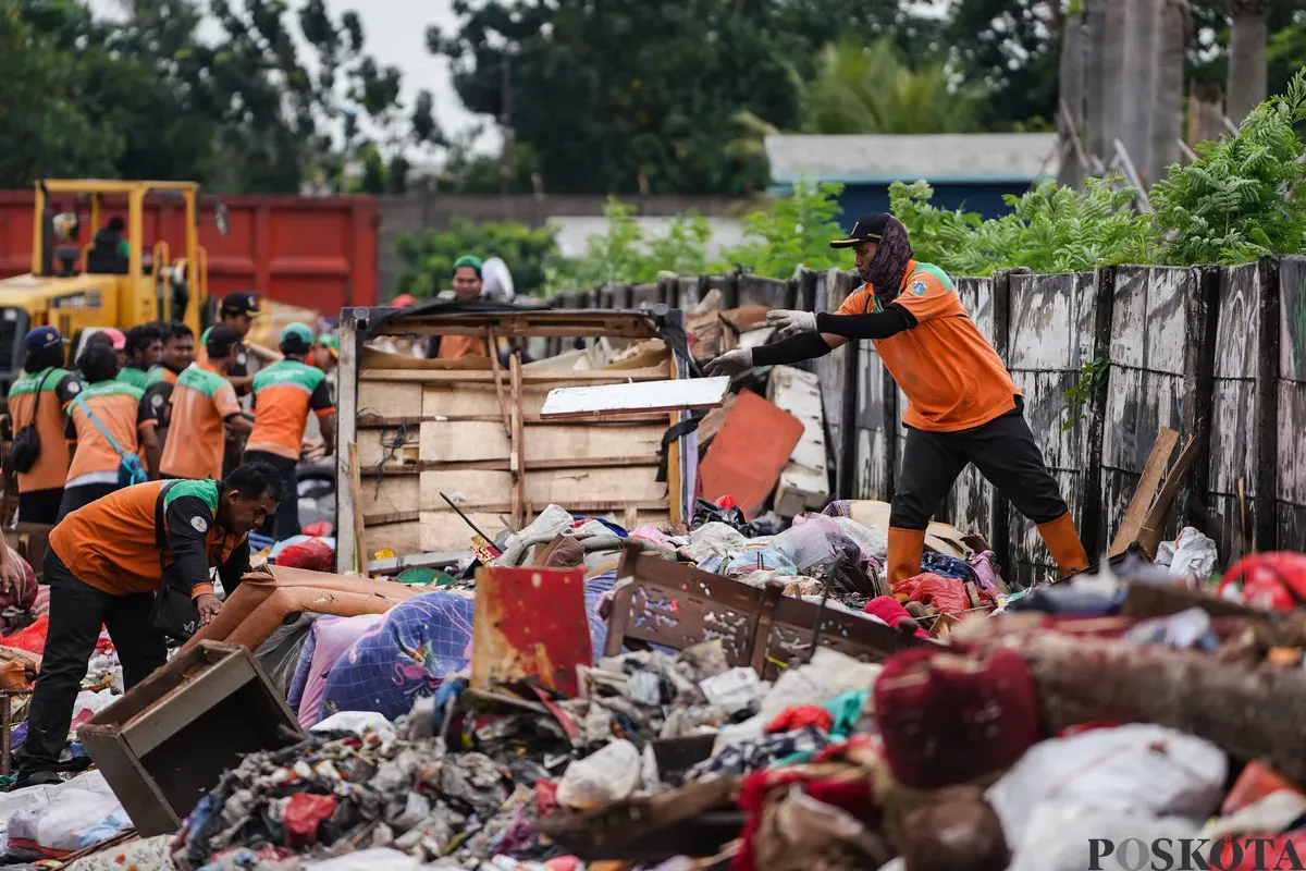 Petugas mengumpulkan sampah sisa banjir yang berasal dari wilayah permukiman kawasan Rawa Buaya di Jalan Inspeksi Kali Mookervart, Daan Mogot, Jakarta, Senin, 26 Januari 2026. (Sumber: Poskota/Bilal Nugraha Ginanjar)