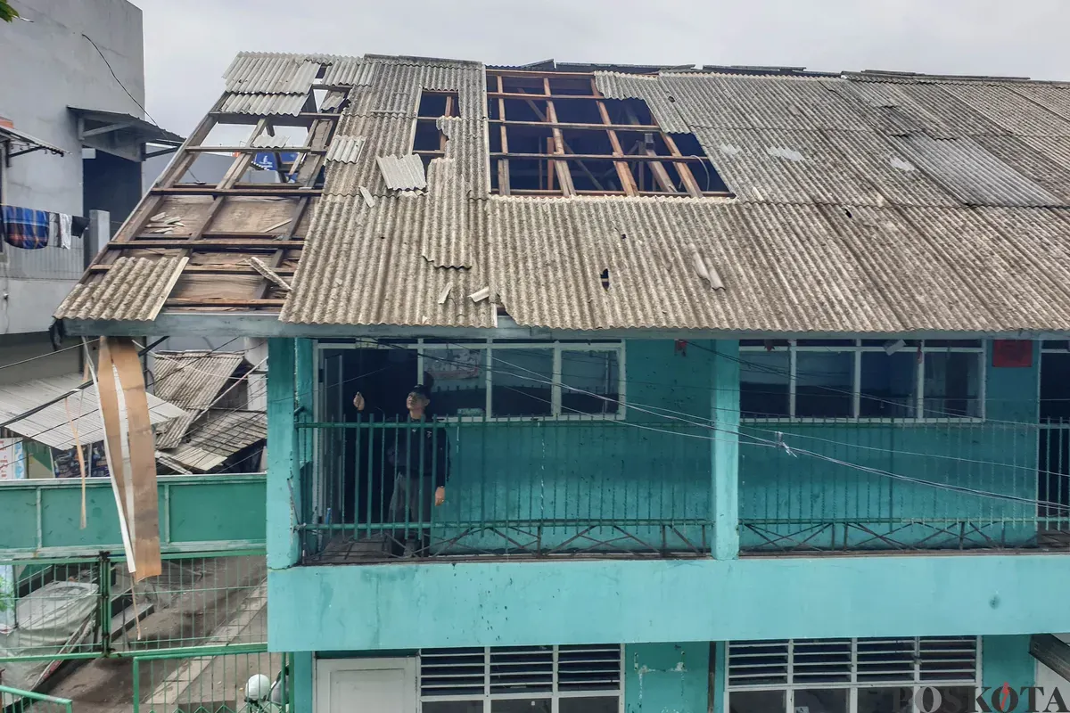 Petugas keamanan memeriksa bangunan yang hancur akibat angin puting beliung di Sekolah Dasar Islam (SDI) Baburidho, Kalibaru, Cilincing, Jakarta Utara, Selasa, 27 Januari 2026. (Sumber: Poskota/Bilal Nugraha Ginanjar)