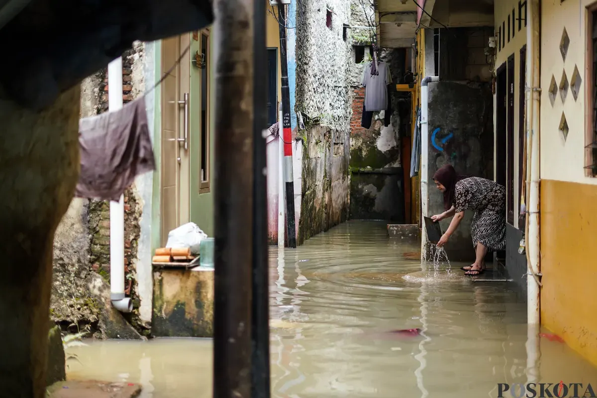 Warga berjalan melintasi banjir yang menggenangi kawasan Kebon Pala, Jakarta Timur, Jumat, 30 Januari 2026 (Sumber: Poskota/Bilal Nugraha Ginanjar)