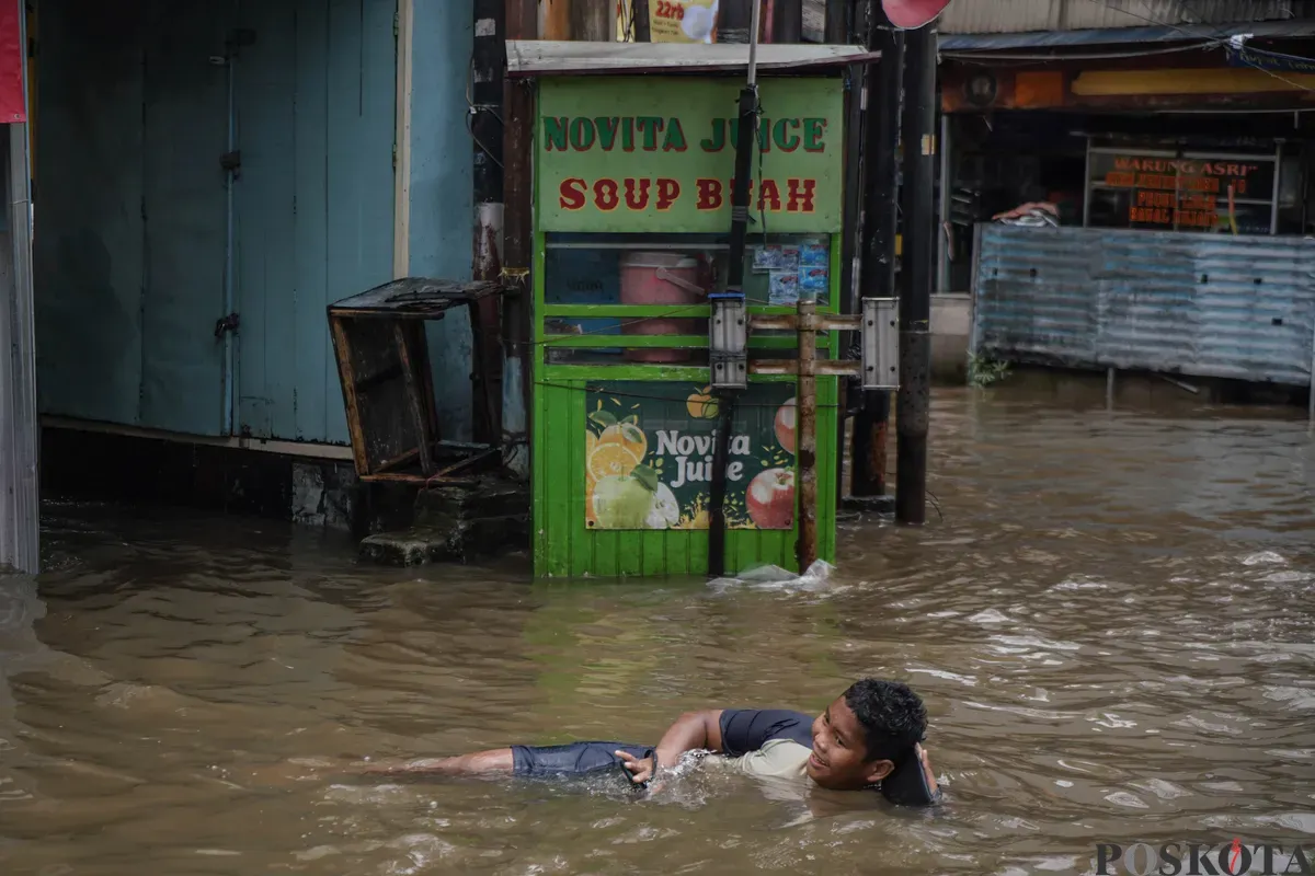 Warga melintasi genagan banjir di Jalan Bendungan Hilir, Jakarta Selatan, Minggu, 8 Maret 2026. (Sumber: Poskota/Bilal Nugraha Ginanjar)