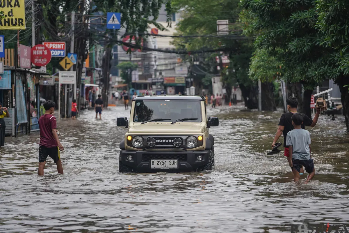 Warga melintasi genagan banjir di Jalan Bendungan Hilir, Jakarta Selatan, Minggu, 8 Maret 2026. (Sumber: Poskota/Bilal Nugraha Ginanjar)
