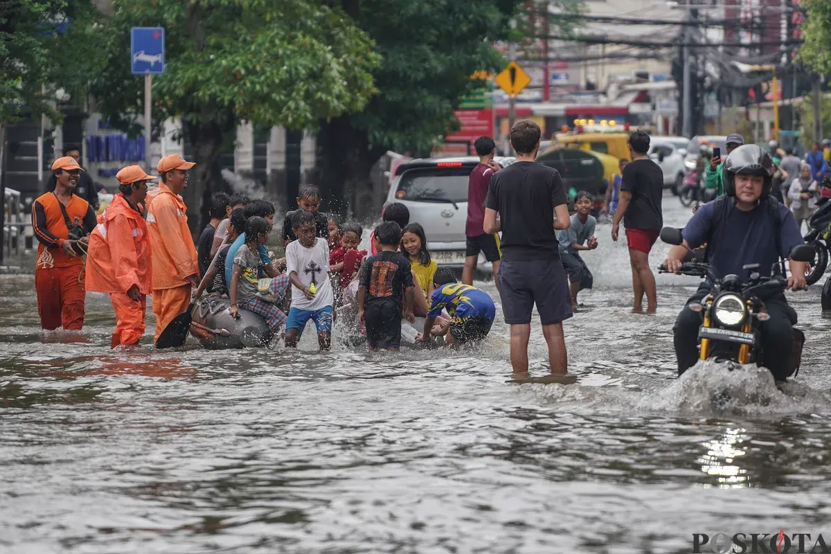 Warga melintasi genagan banjir di Jalan Bendungan Hilir, Jakarta Selatan, Minggu, 8 Maret 2026. (Sumber: Poskota/Bilal Nugraha Ginanjar)