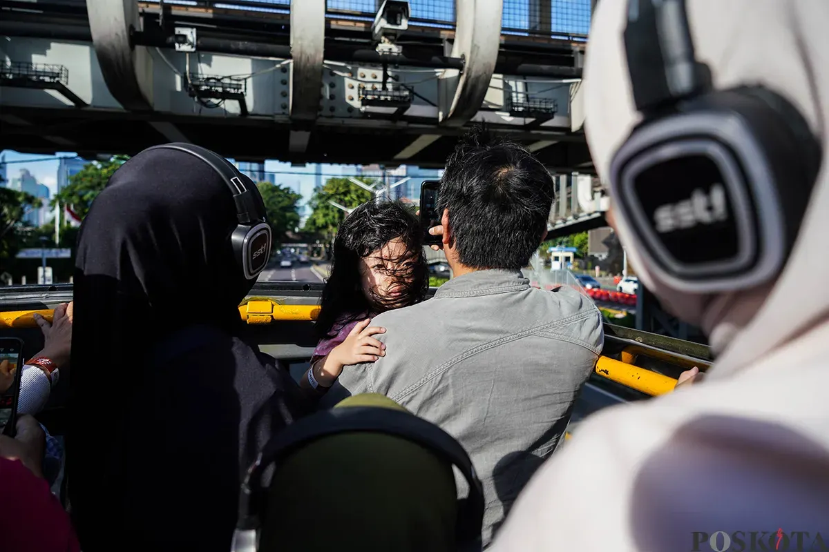 Pengunjung menikmati suasana bersama keluarga sambil berswafoto dengan latar belakang kota dari bagian atap bus wisata Open Top Tour of Jakarta, Jumat, 4 April 2025. (Sumber: Poskota/Bilal Nugraha Ginanjar)
