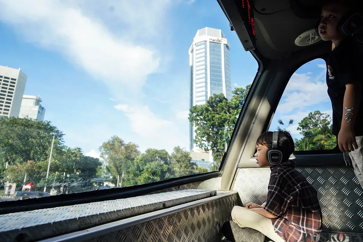 Pengunjung menikmati suasana bersama keluarga sambil berswafoto dengan latar belakang kota dari bagian atap bus wisata Open Top Tour of Jakarta, Jumat, 4 April 2025. (Sumber: Poskota/Bilal Nugraha Ginanjar)