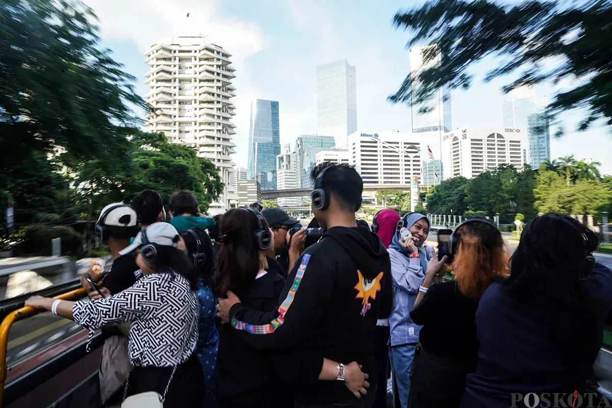 Pengunjung menikmati suasana bersama keluarga sambil berswafoto dengan latar belakang kota dari bagian atap bus wisata Open Top Tour of Jakarta, Jumat, 4 April 2025. (Sumber: Poskota/Bilal Nugraha Ginanjar)