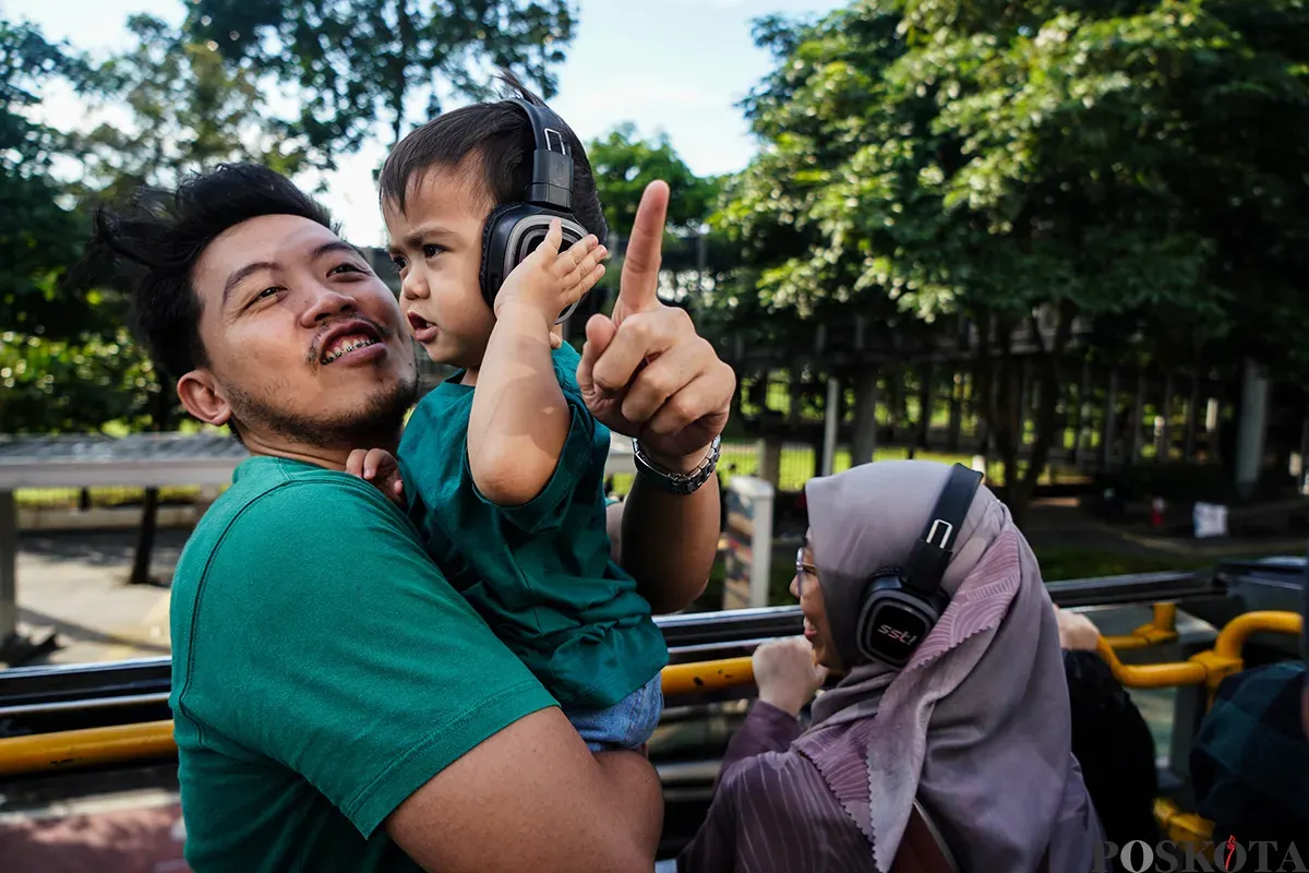 Pengunjung menikmati suasana bersama keluarga sambil berswafoto dengan latar belakang kota dari bagian atap bus wisata Open Top Tour of Jakarta, Jumat, 4 April 2025. (Sumber: Poskota/Bilal Nugraha Ginanjar)