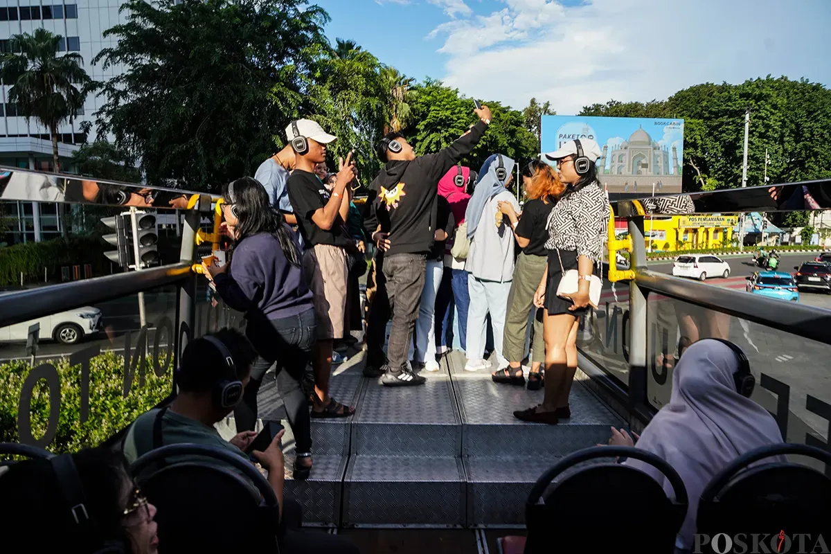 Pengunjung menikmati suasana bersama keluarga sambil berswafoto dengan latar belakang kota dari bagian atap bus wisata Open Top Tour of Jakarta, Jumat, 4 April 2025. (Sumber: Poskota/Bilal Nugraha Ginanjar)