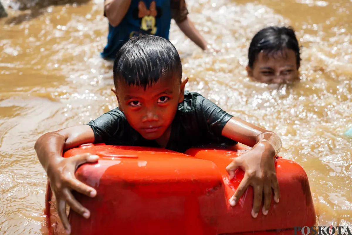 Dokumentasi - Seorang anak memegang wadah plastik sebagai pelampung saat banjir merendam permukiman warga di Jakarta, Selasa, 4 Maret 2025. Banjir terjadi akibat hujan deras dan luapan sungai. (Sumber: Poskota/Bilal Nugraha Ginanjar)