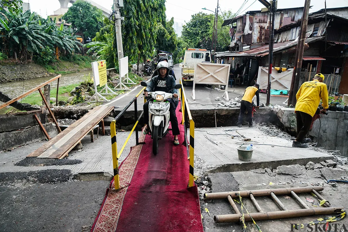 Warga melintas di jembatan sementara menggunakan sepeda motor di Jalan Kesatriaan X, Kebon Manggis, Matraman, Jakarta Timur, Kamis, 10 April 2025. (Sumber: Poskota/Bilal Nugraha Ginanjar)
