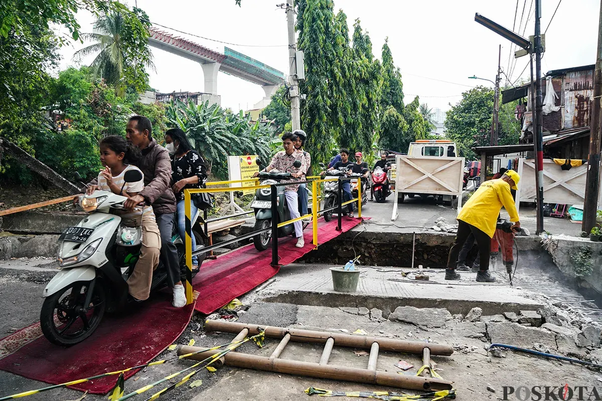 Warga melintas di jembatan sementara menggunakan sepeda motor di Jalan Kesatriaan X, Kebon Manggis, Matraman, Jakarta Timur, Kamis, 10 April 2025. (Sumber: Poskota/Bilal Nugraha Ginanjar)
