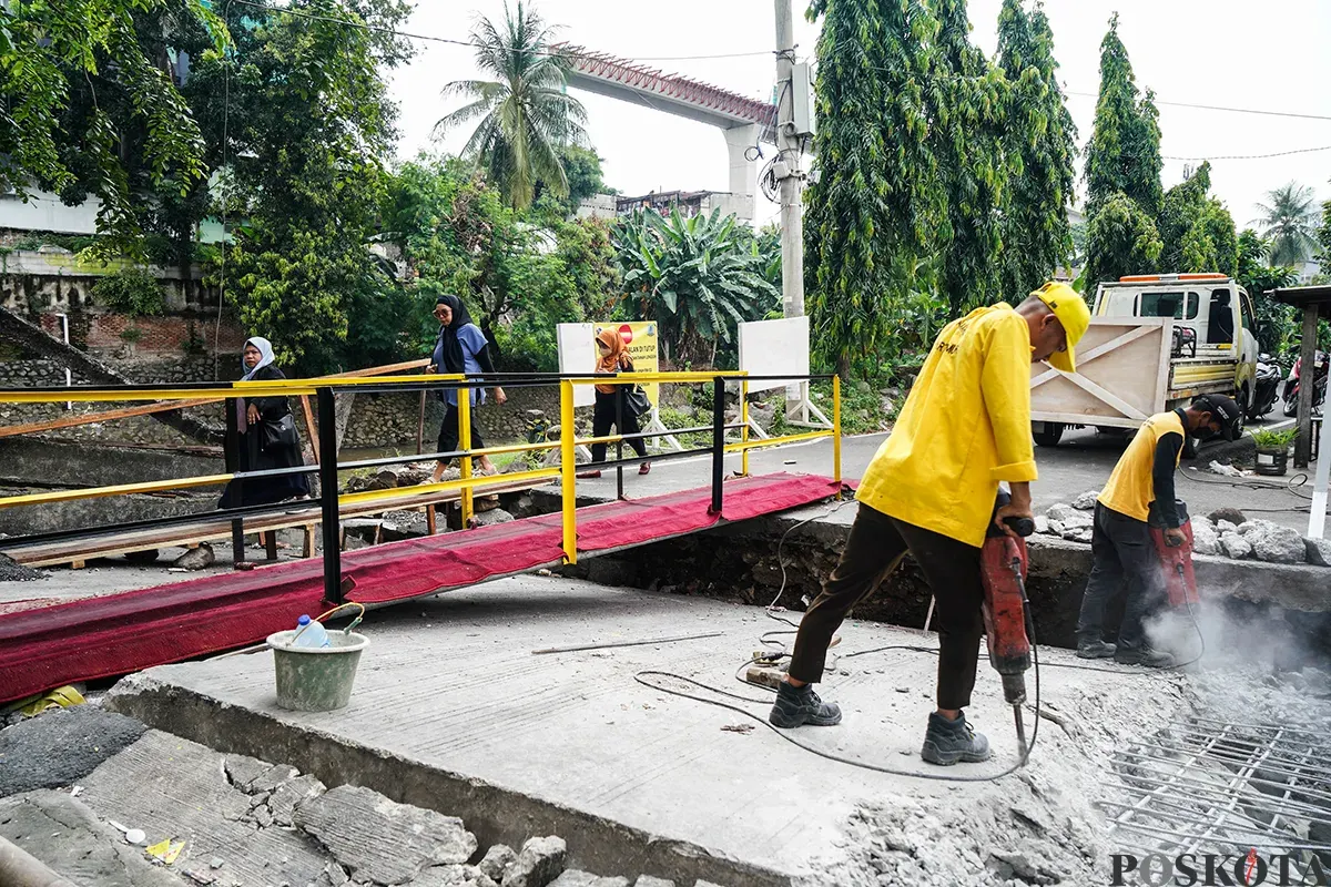 Warga melintas di jembatan sementara menggunakan sepeda motor di Jalan Kesatriaan X, Kebon Manggis, Matraman, Jakarta Timur, Kamis, 10 April 2025. (Sumber: Poskota/Bilal Nugraha Ginanjar)