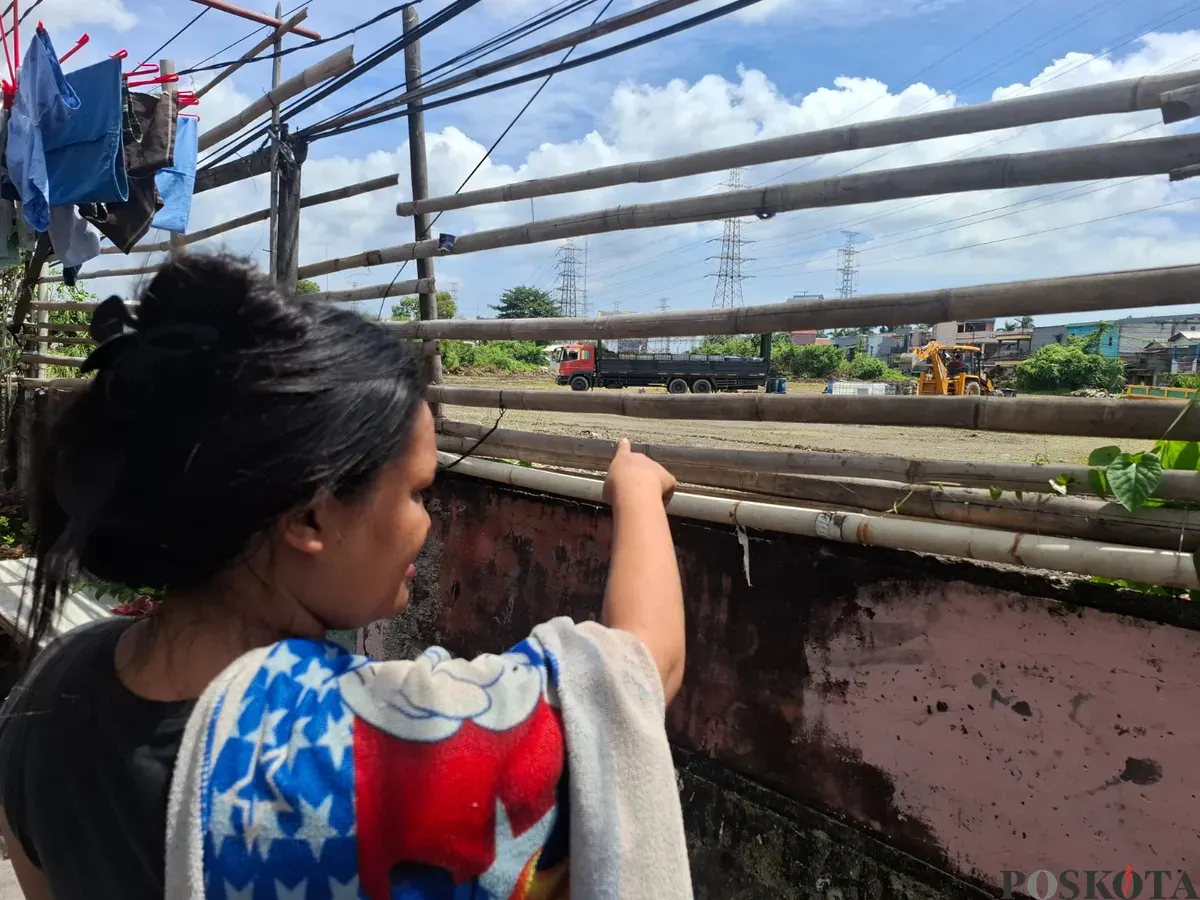 Seorang warga menunjuk ke arah lapangan tempat penyimpanan drum berisi limbah cair milik PT Elnusa Petrofin di Kampung Tanah Merah, Koja, Jakarta Utara. (Sumber: Poskota/Angga Pahlevi)
