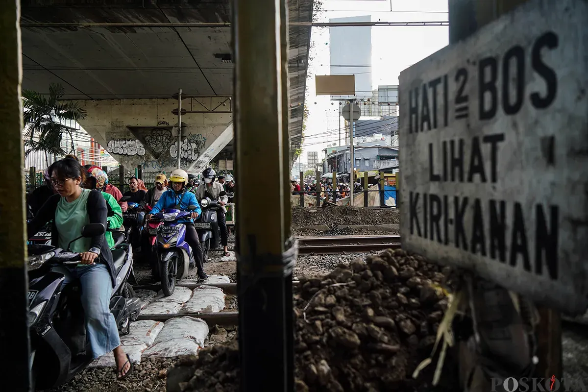 Sejumlah pengendara sepeda motor mengantre saat melintasi akses perlintasan kereta api tanpa palang pintu di bawah Fylover Roxy, Duri, Jakarta, Senin (14/4). (Sumber: Poskota/Bilal Nugraha Ginanjar)