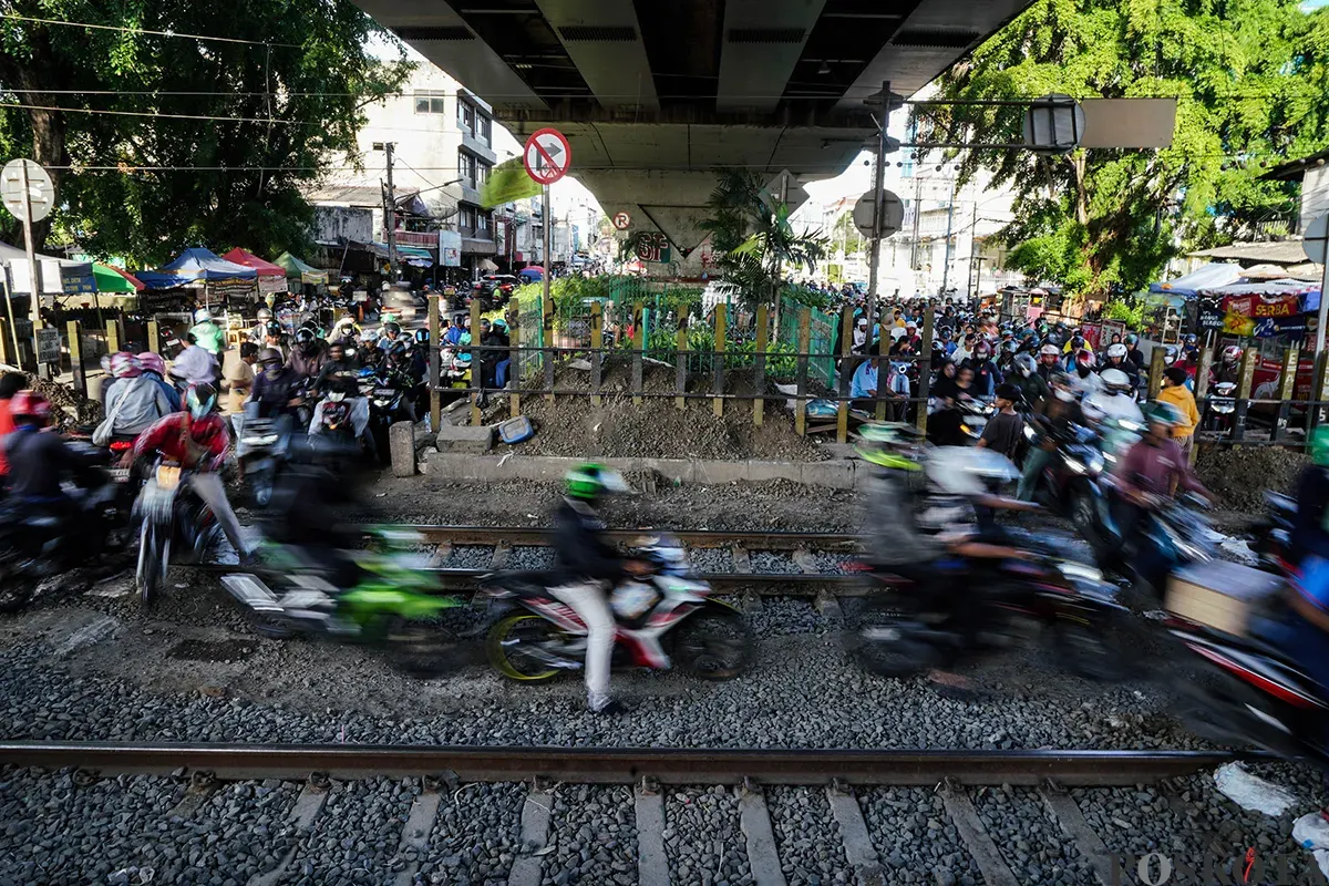 Sejumlah pengendara sepeda motor mengantre saat melintasi akses perlintasan kereta api tanpa palang pintu di bawah Fylover Roxy, Duri, Jakarta, Senin (14/4). (Sumber: Poskota/Bilal Nugraha Ginanjar)