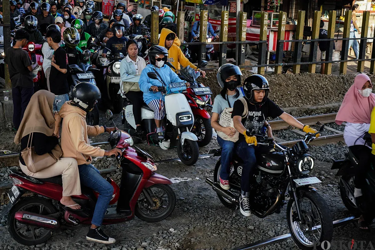 Sejumlah pengendara sepeda motor mengantre saat melintasi akses perlintasan kereta api tanpa palang pintu di bawah Fylover Roxy, Duri, Jakarta, Senin (14/4). (Sumber: Poskota/Bilal Nugraha Ginanjar)