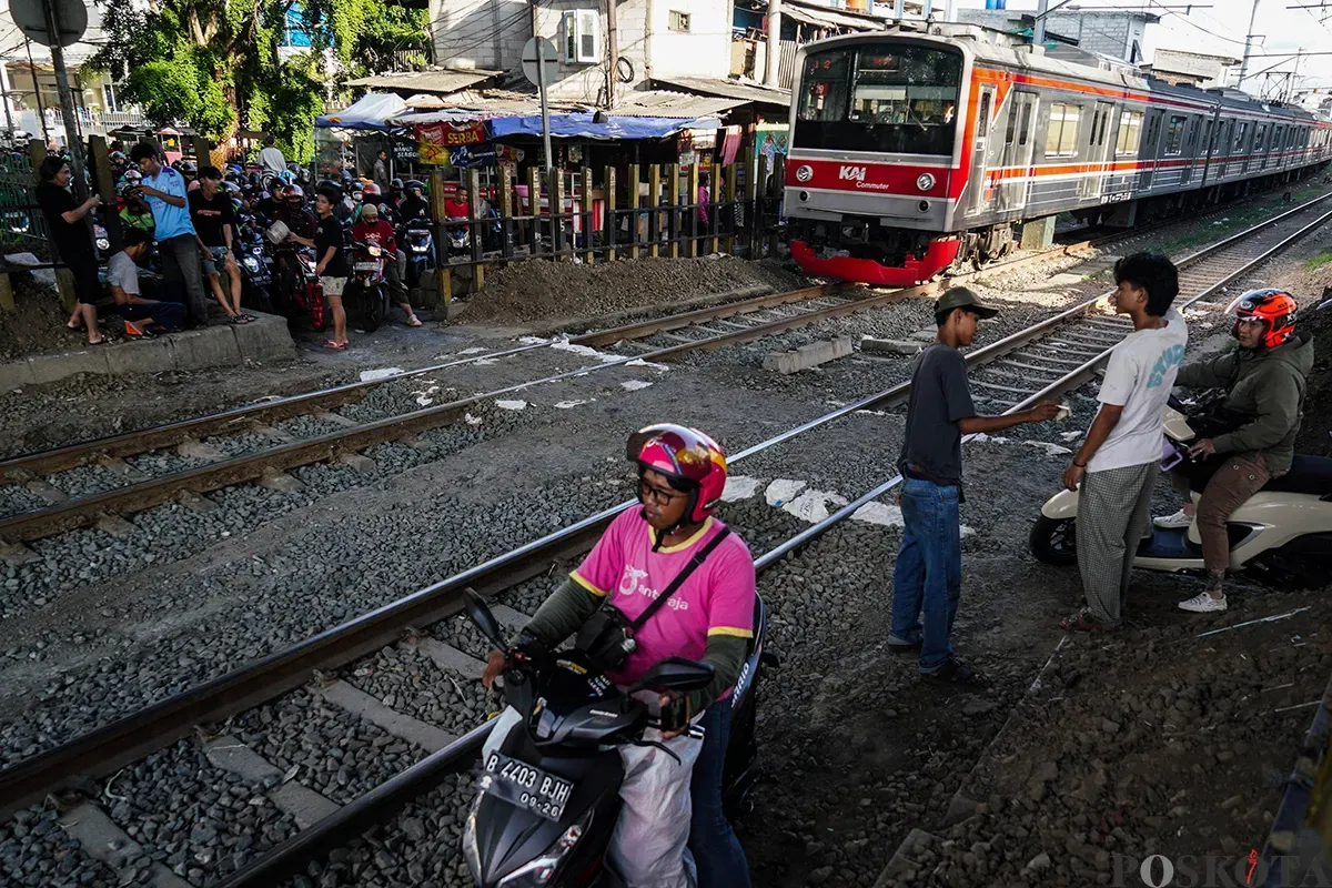 Sejumlah pengendara sepeda motor mengantre saat melintasi akses perlintasan kereta api tanpa palang pintu di bawah Fylover Roxy, Duri, Jakarta, Senin (14/4). (Sumber: Poskota/Bilal Nugraha Ginanjar)