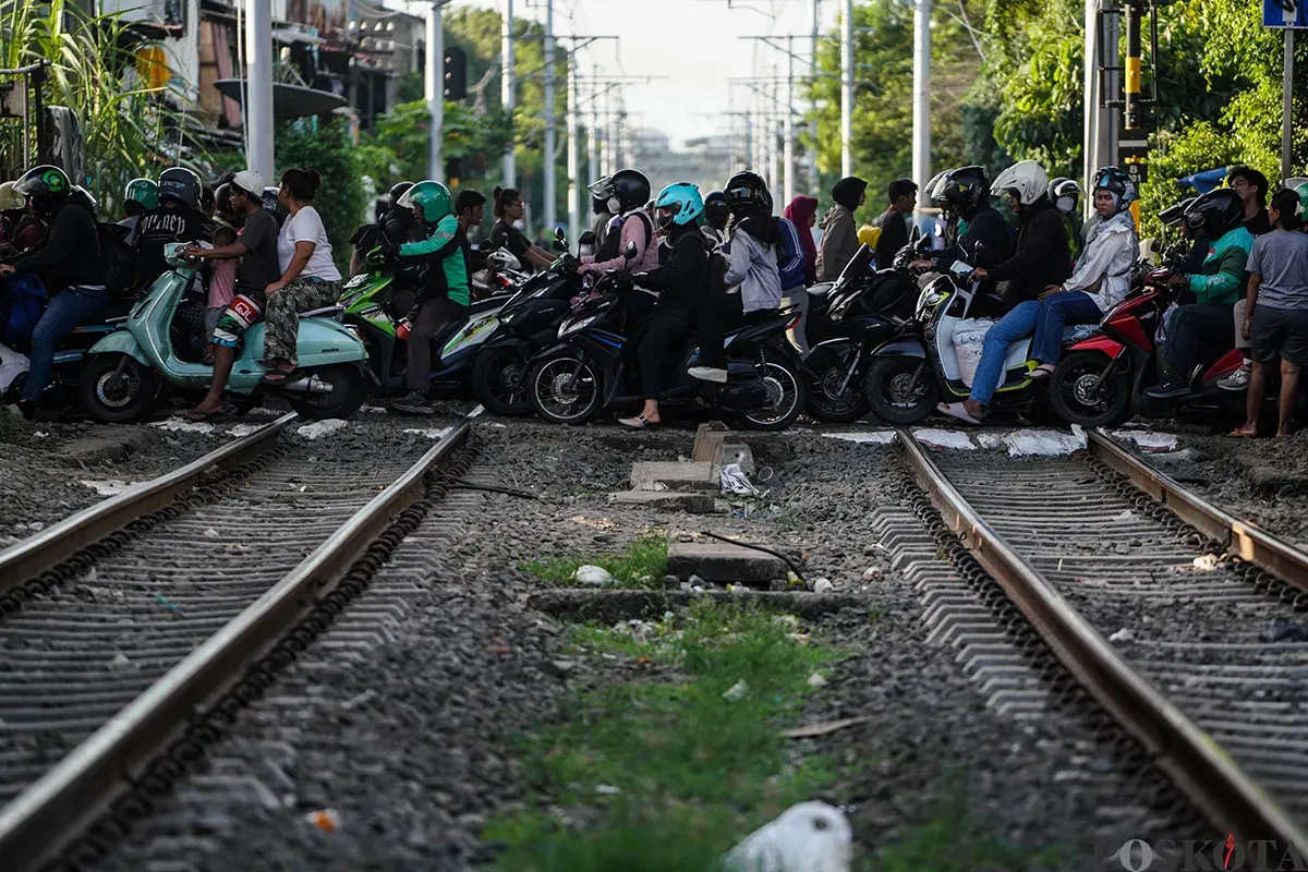 Sejumlah pengendara sepeda motor mengantre saat melintasi akses perlintasan kereta api tanpa palang pintu di bawah Fylover Roxy, Duri, Jakarta, Senin (14/4). (Sumber: Poskota/Bilal Nugraha Ginanjar)