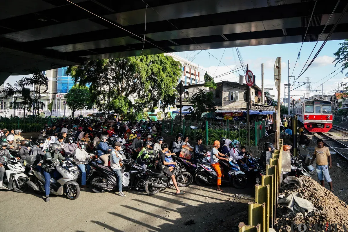 Sejumlah pengendara sepeda motor mengantre saat melintasi akses perlintasan kereta api tanpa palang pintu di bawah Fylover Roxy, Duri, Jakarta, Senin (14/4). (Sumber: Poskota/Bilal Nugraha Ginanjar)
