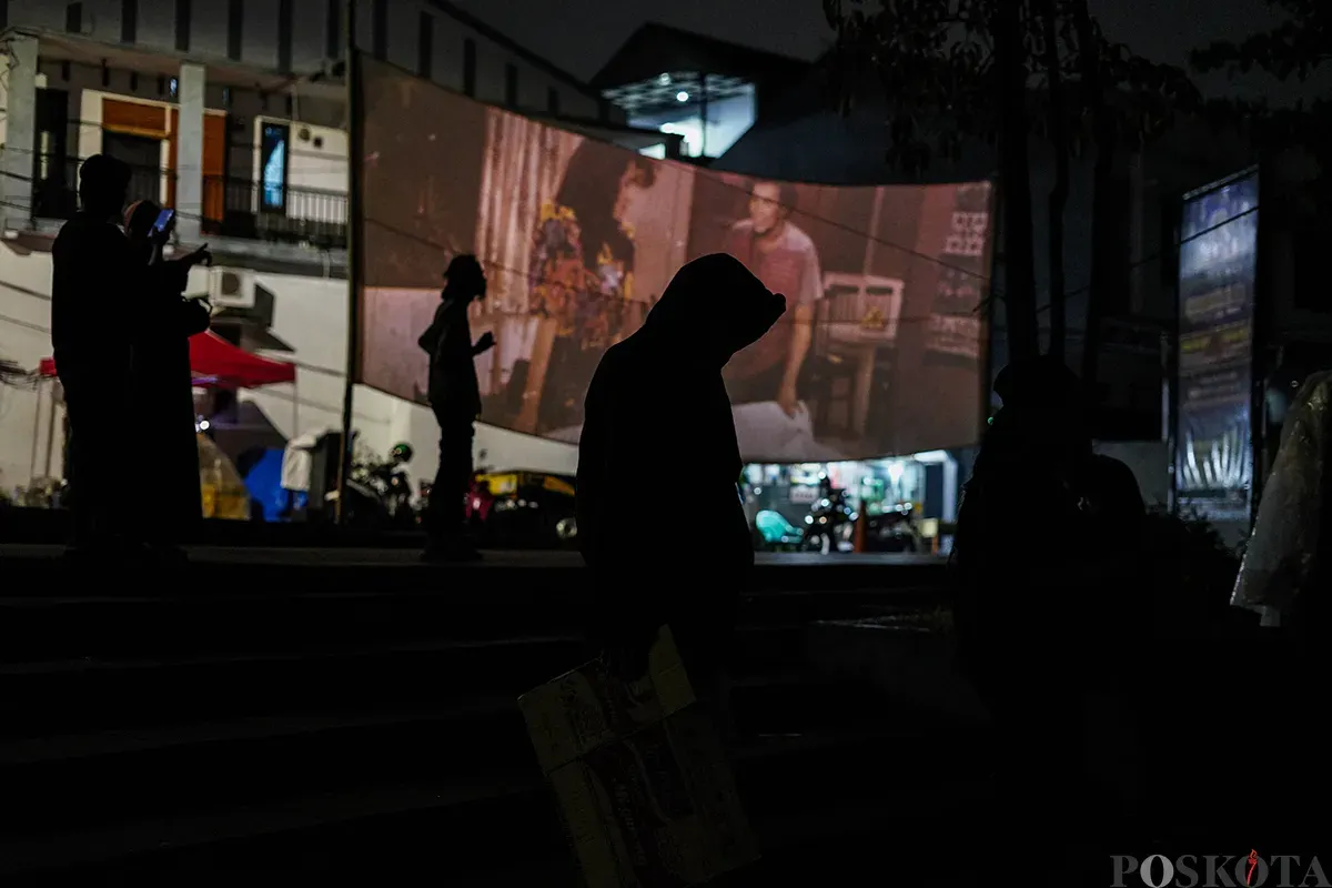 Operator film layar tancap memutarkan rol film era menggunakan mesin proyektor di Waduk Lebak Bulus, Jakarta Selatan, Jum'at, 18 April 2025. (Sumber: Poskota/Bilal Nugraha Ginanjar)