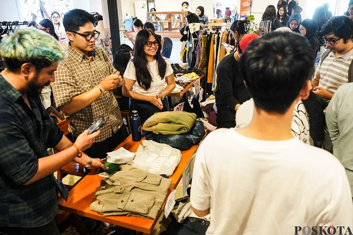 Pengunjung memilah dan memilih aneka merek pakaian bekas atau preloved yang sempat dikenakan oleh sejumlah influencer di lapak penjualan busana di Kuru Ground, Tebet, Jakarta Selatan, Sabtu, 19 April 2025. (Sumber: Poskota/Bilal Nugraha Ginanjar)