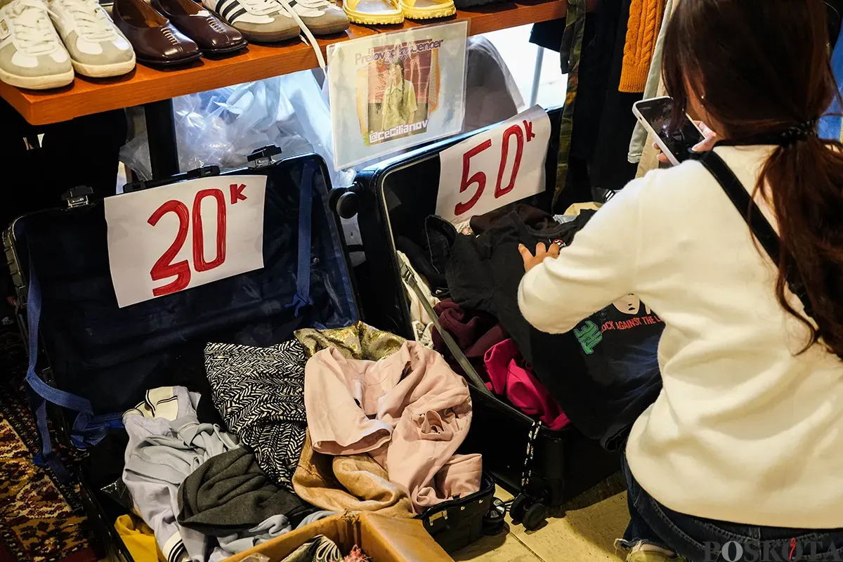 Pengunjung memilah dan memilih aneka merek pakaian bekas atau preloved yang sempat dikenakan oleh sejumlah influencer di lapak penjualan busana di Kuru Ground, Tebet, Jakarta Selatan, Sabtu, 19 April 2025. (Sumber: Poskota/Bilal Nugraha Ginanjar)