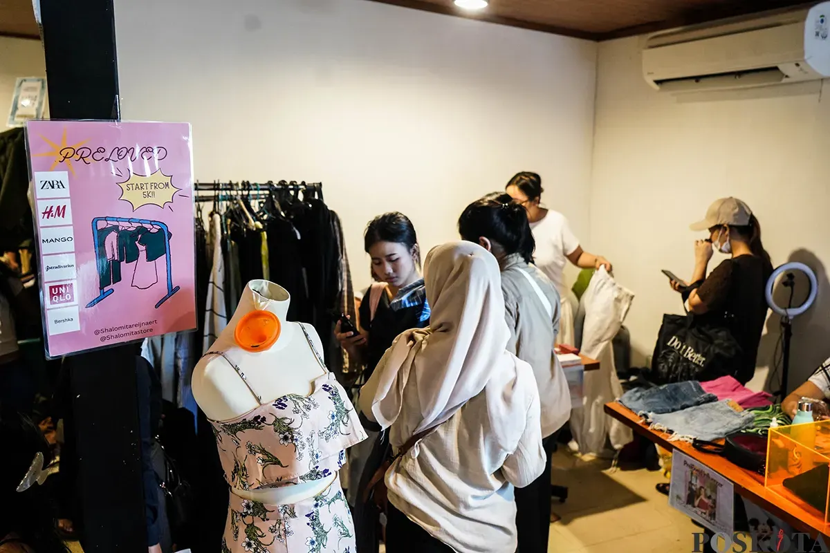 Pengunjung memilah dan memilih aneka merek pakaian bekas atau preloved yang sempat dikenakan oleh sejumlah influencer di lapak penjualan busana di Kuru Ground, Tebet, Jakarta Selatan, Sabtu, 19 April 2025. (Sumber: Poskota/Bilal Nugraha Ginanjar)