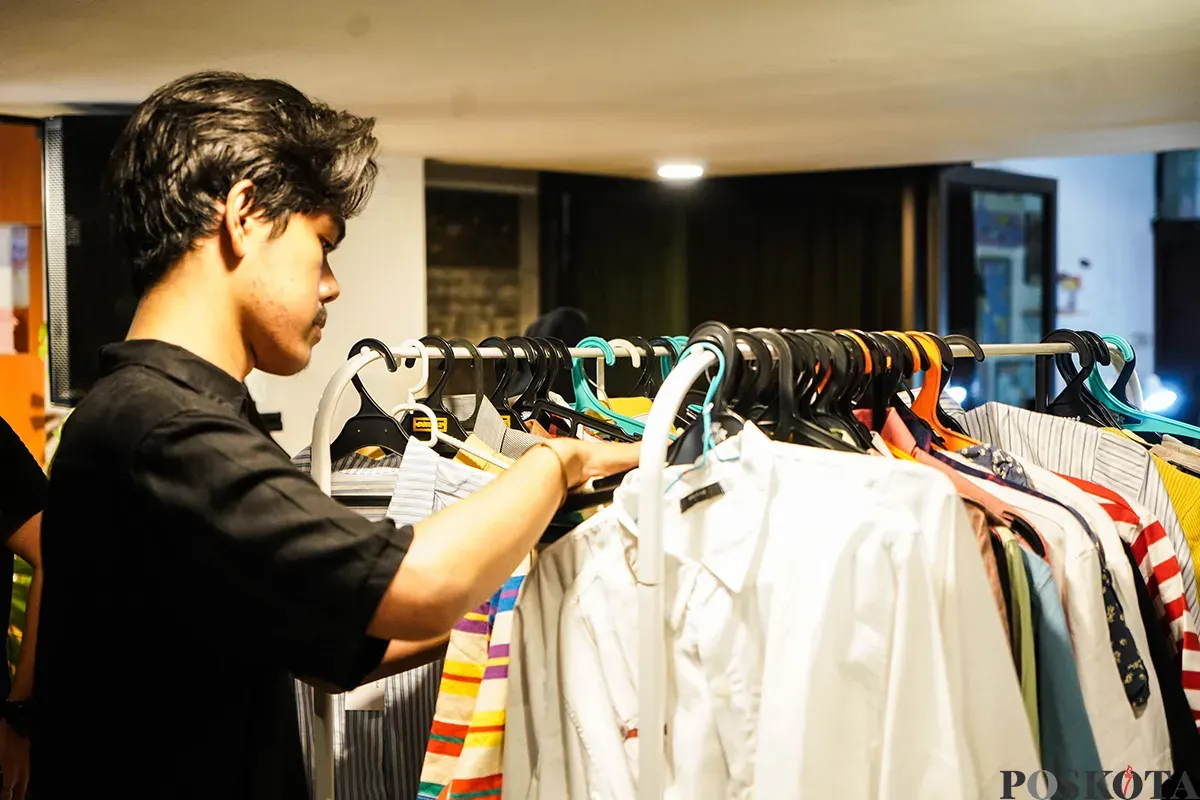 Pengunjung memilah dan memilih aneka merek pakaian bekas atau preloved yang sempat dikenakan oleh sejumlah influencer di lapak penjualan busana di Kuru Ground, Tebet, Jakarta Selatan, Sabtu, 19 April 2025. (Sumber: Poskota/Bilal Nugraha Ginanjar)