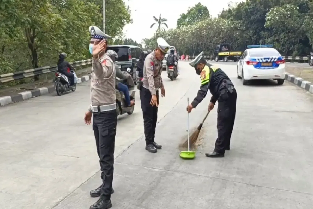 Petugas Lantas Polres Metro Depok membersihkan ceceran oli di jalan Fly Over UI, yang membuat pemotor berjatuhan, Minggu, 20 April 2025, siang. (Sumber: Satlantas Polres Metro Depok)