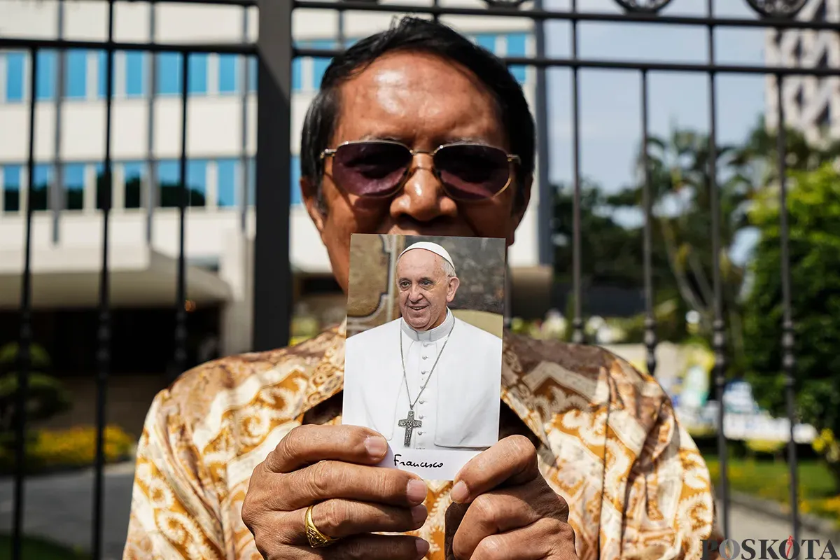Umat Katolik memperlihatkan foto Paus Fransiskus. (Sumber: Poskota/Bilal Nugraha Ginanjar)