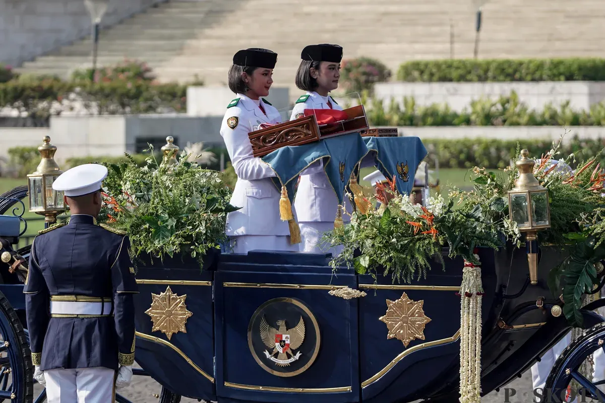 Purna Paskibraka Duta Pancasila 2024, Kirana Ashawidya Baskara dan Ni Komang Tri Setia membawa baki Bendera Pusaka Merah Putih dan Teks Proklamasi saat menaiki Kereta Kencana Garuda Prabayeksa pada Kirab Merah Putih HUT ke-80 Republik Indonesia di Monas, Jakarta, Minggu, 17 Agustus 2025 (Sumber: Poskota/Bilal Nugraha Ginanjar)