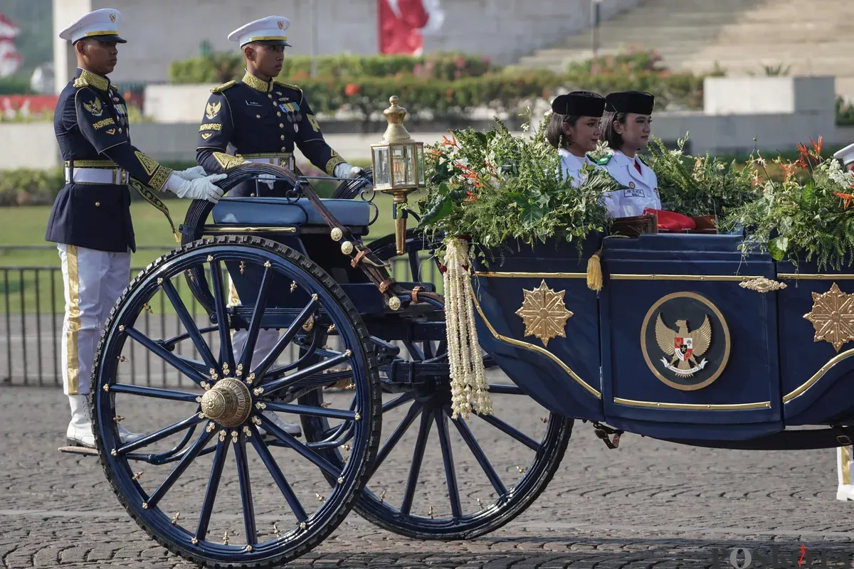 Purna Paskibraka Duta Pancasila 2024, Kirana Ashawidya Baskara dan Ni Komang Tri Setia membawa baki Bendera Pusaka Merah Putih dan Teks Proklamasi saat menaiki Kereta Kencana Garuda Prabayeksa pada Kirab Merah Putih HUT ke-80 Republik Indonesia di Monas, Jakarta, Minggu, 17 Agustus 2025 (Sumber: Poskota/Bilal Nugraha Ginanjar)