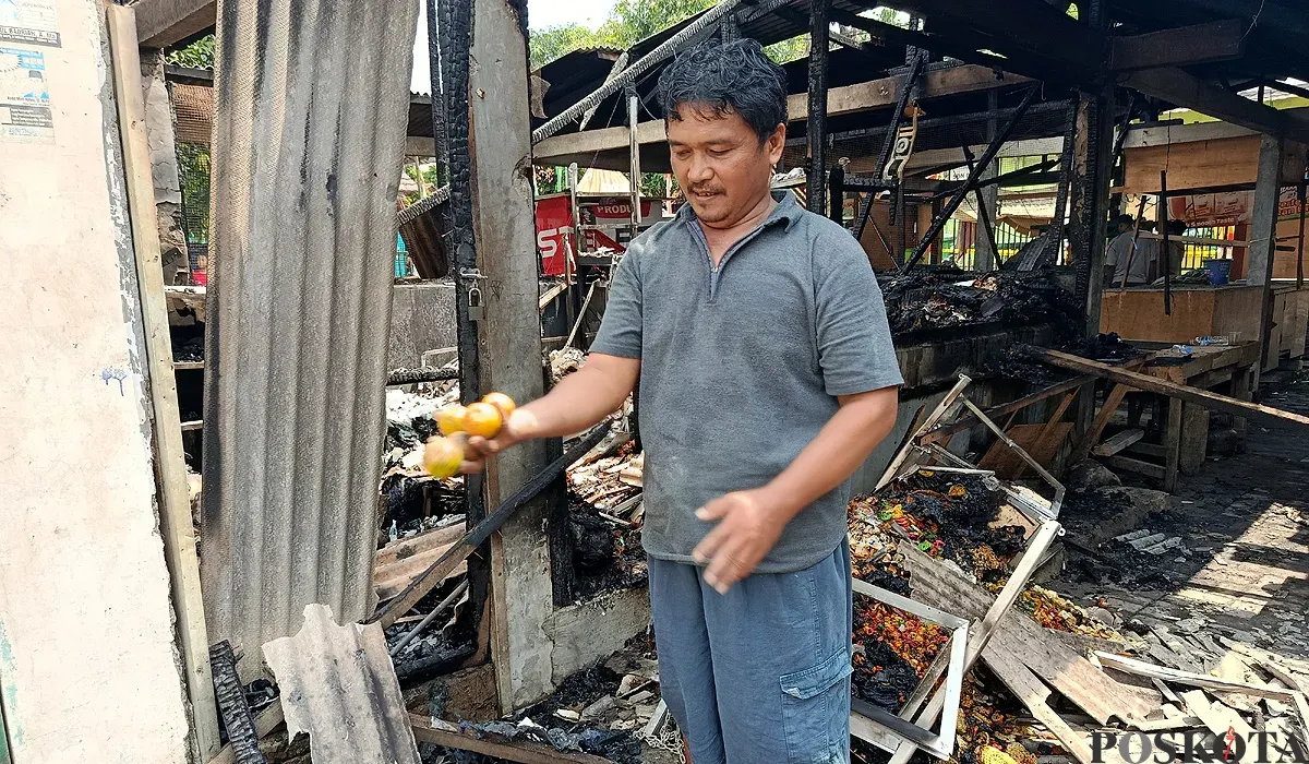 Asep, salah satu pedagang Pasar Pejuang Pratama, mengais buah jeruk miliknya yang tersisa di antara puing dan arang bekas kebakaran, Minggu 24 Agustus 2025. (Sumber: POSKOTA | Foto: Nurpini Aulia Rapika)