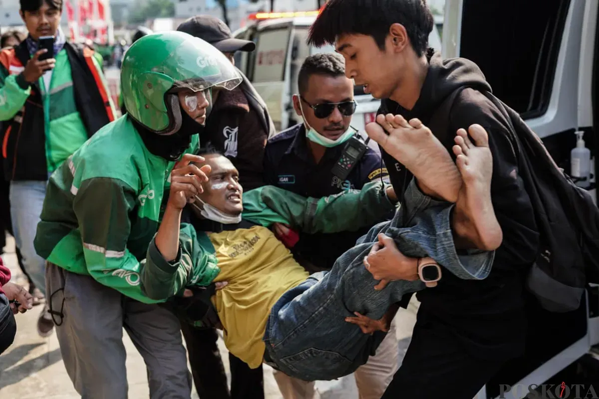 Seorang massa aksi beratribut ojek online (ojol) digotong saat demonstrasi di Satuan Brimob Polda Metro Jaya, Kecamatan Senen, Jakarta Pusat, Jumat, 29 Agustus 2025. (Sumber: Poskota/Bilal Nugraha Ginanjar)