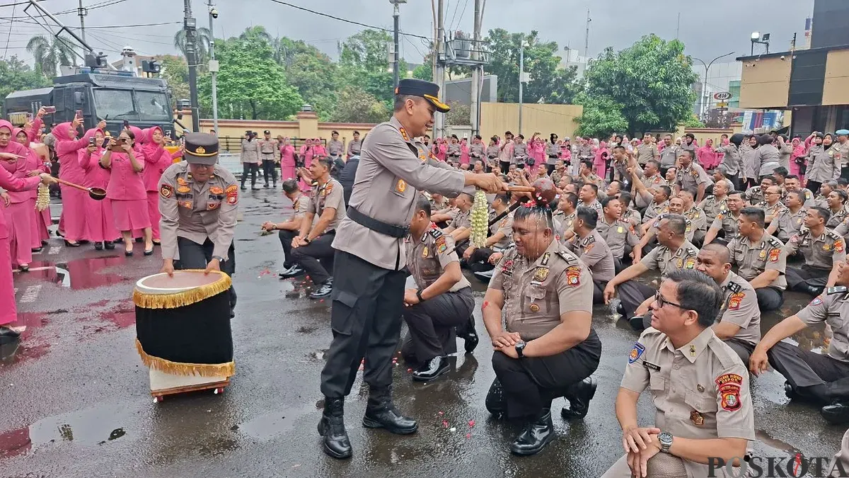 Kapolres Metro Depok, Kombes Pol Abdul Waras melakukan tradisi siram air kembang kepada personel yang naik pangkat di Mapolres Metro Depok, Rabu, 31 Desember 2025. (Sumber: Poskota/Angga Pahlevi)