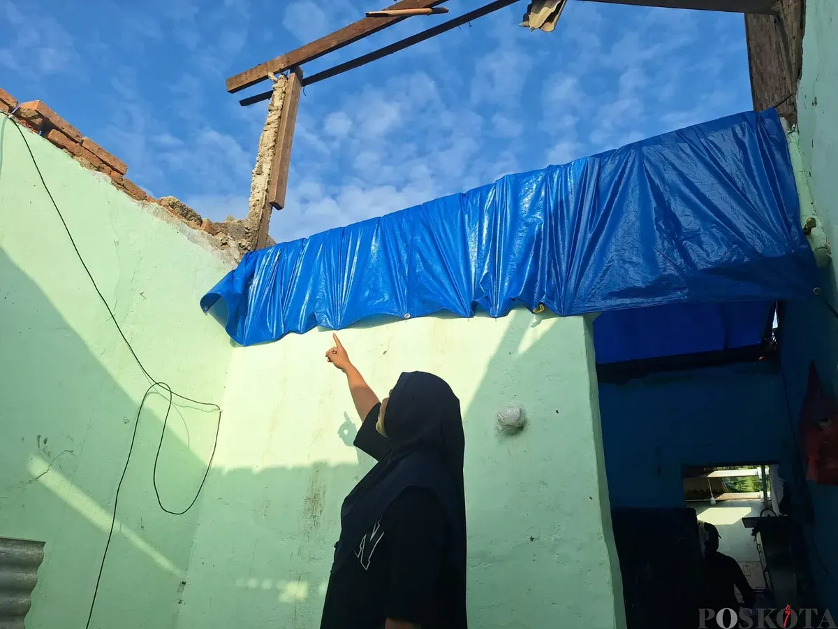 Iip Fajriyati, 28 tahun, menunjuk plafon rumahnya yang hancur tersapu puting beliung di Kampung Buwek, Desa Sumber Jaya, Tambun Selatan, Kabupaten Bekasi, Jumat, 7 Februari 2025. (Sumber: Poskota/Ihsan Fahmi)