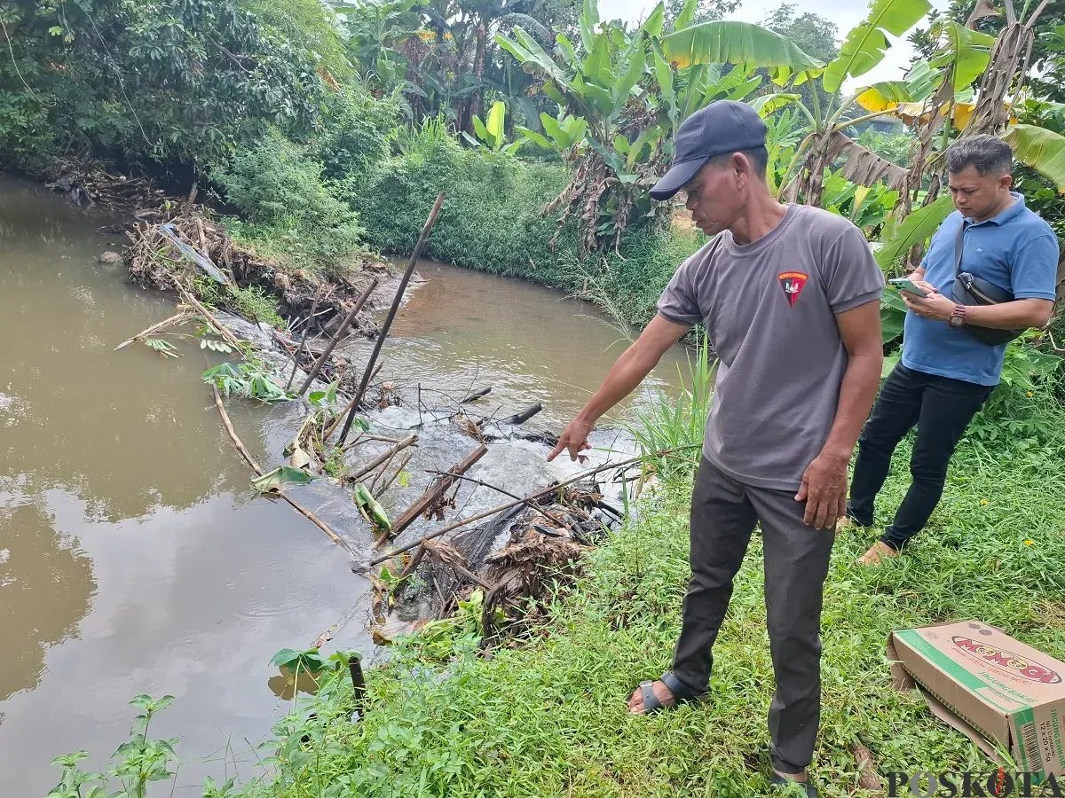 Ketua RT 2/01 Desa Nanggerang, Kecamatan Tajurhalang, Wawih bersama anggota Opsnal Kecamatan Tajurhalang mengecek lokasi penemuan jasad bayi di Kali Caringin, Sabtu 8 Februari 2025. (Sumber: Poskota/Angga Pahlevi)