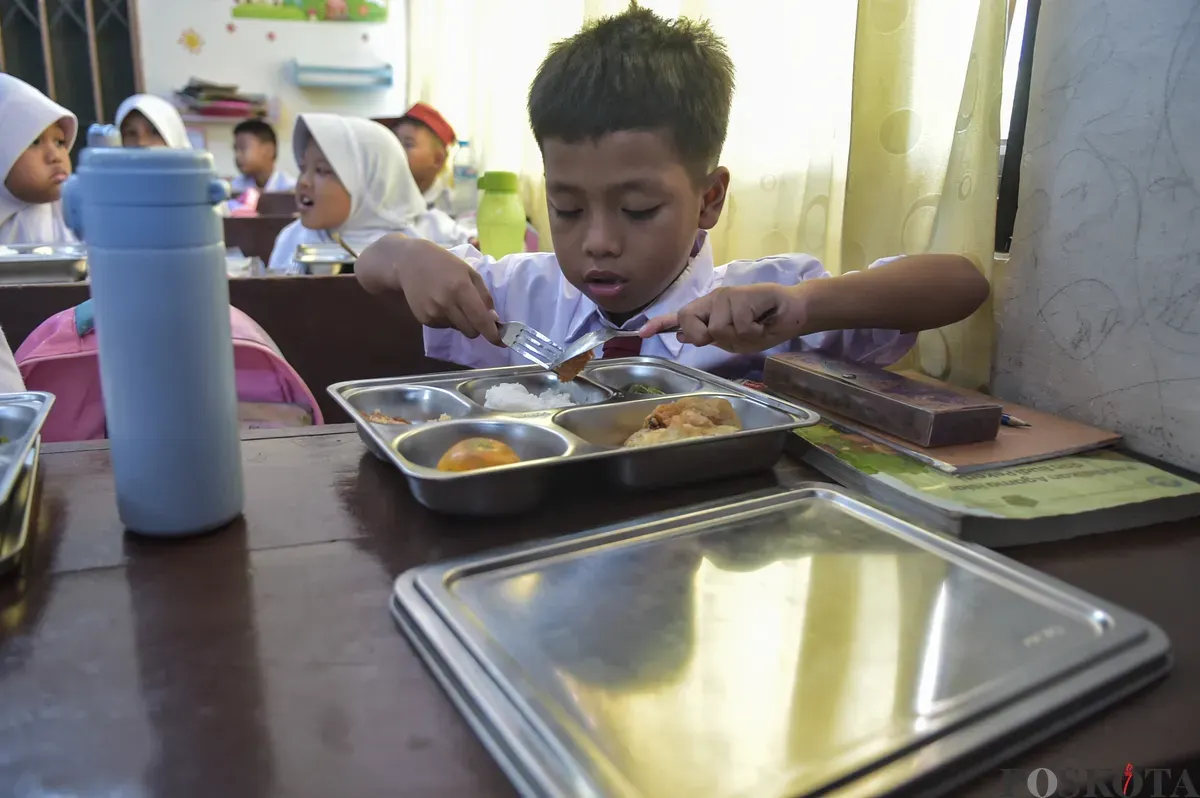 Sejumlah siswa menyantap menu makan siang dari program Makan Bergizi Gratis (MBG) Nasional di ruang kelas SDN Slipi 15, Jakarta Barat, Senin, 6 Januari 2025. (Sumber: Poskoata/ Bilal Nugraha Ginanjar)