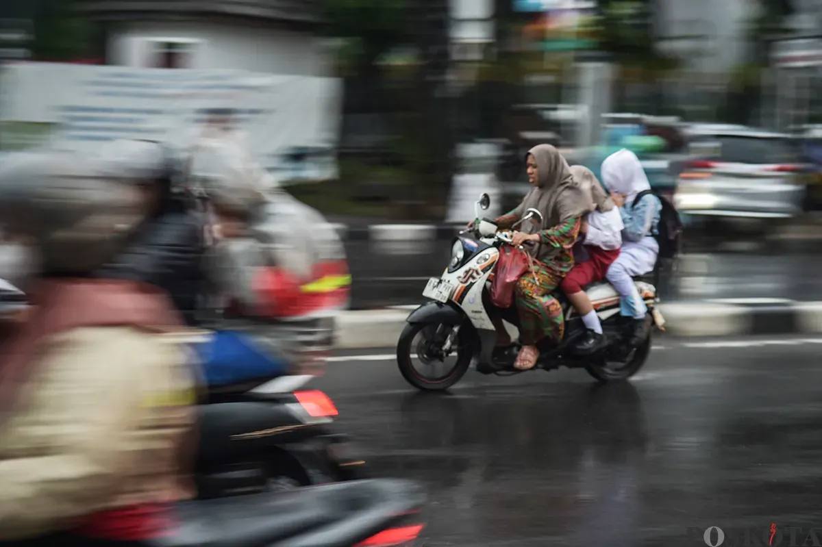 Pengendara sepeda motor tanpa menggunakan helm keselamatan saat diguyur hujan di Jalan K.H. Mas Mansyur, Jakarta Pusat, Kamis, 9 Januari 2025. (Sumber: Poskota/ Bilal Nugraha Ginanjar)