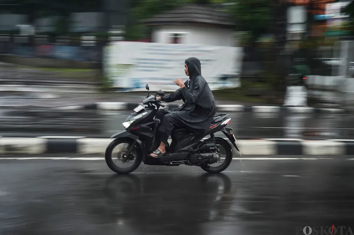 Pengendara sepeda motor tanpa menggunakan helm keselamatan saat diguyur hujan di Jalan K.H. Mas Mansyur, Jakarta Pusat, Kamis, 9 Januari 2025. (Sumber: Poskota/ Bilal Nugraha Ginanjar)