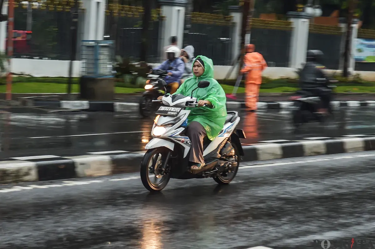Pengendara sepeda motor tanpa menggunakan helm keselamatan saat diguyur hujan di Jalan K.H. Mas Mansyur, Jakarta Pusat, Kamis, 9 Januari 2025. (Sumber: Poskota/ Bilal Nugraha Ginanjar)