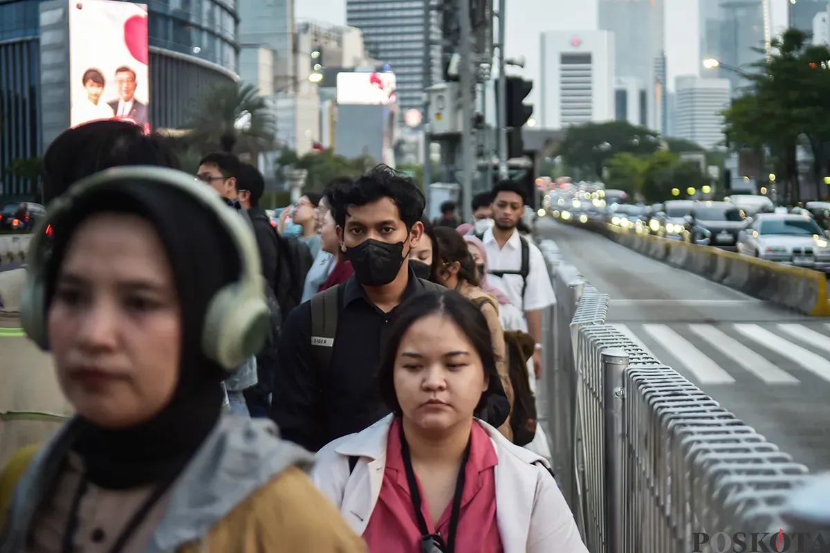 Para pekerja berjalan melintasi pedestrian sesaat setelah jam pulang kerja di kawasan Jalan Jenderal Sudirman, Jakarta, Jumat, 10 Januari 2025. (Sumber: Poskota/ Bilal Nugraha Ginanjar)